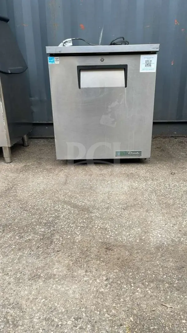 TRUE TUC-27-HC undercounter refrigerator, stainless steel, visible wear, model and energy labels on front.