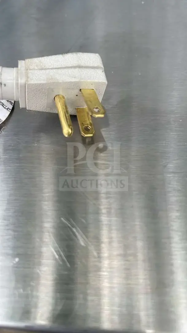 Close-up of True TUC-27-HC undercounter refrigerator plug on stainless steel surface.