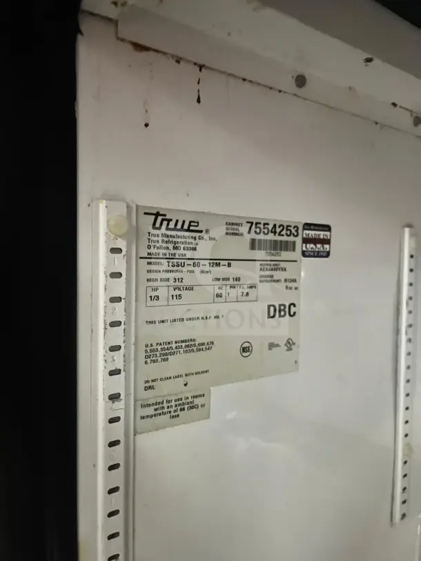 Close-up of a label on a True TSSU-60-12M refrigerated pizza prep table, displaying model details and specifications.