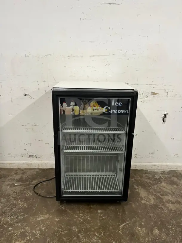 White countertop display ice cream freezer with a glass door, excellent condition, featuring two shelves and ice cream graphics.