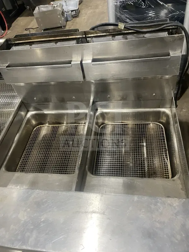 Keating stainless steel dual fryer, Model 14TSSI, natural gas, 120V 1 Phase, on casters, with heating element and backsplash.