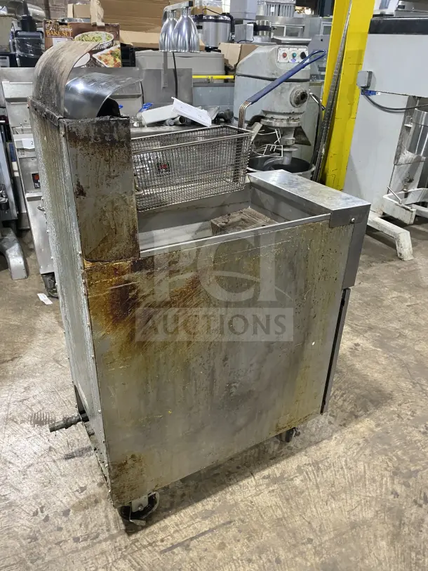 Frymaster commercial stainless steel gas-powered deep fat fryer with backsplash, basket hanger, and fry basket on casters. Used condition.