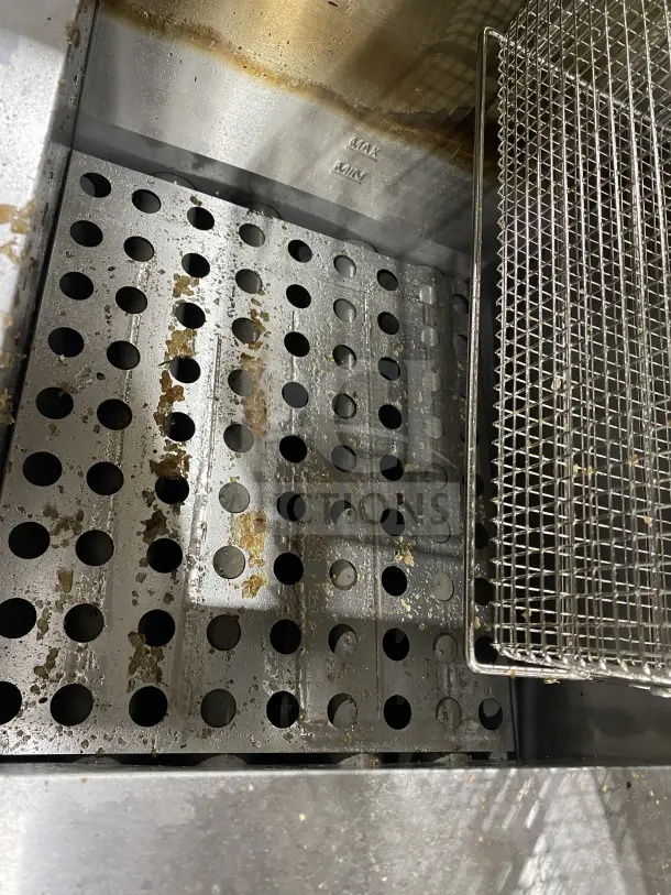 Globe GF30G commercial stainless steel natural gas countertop fryer with backsplash, basket hanger, and fry baskets. Some residue visible.