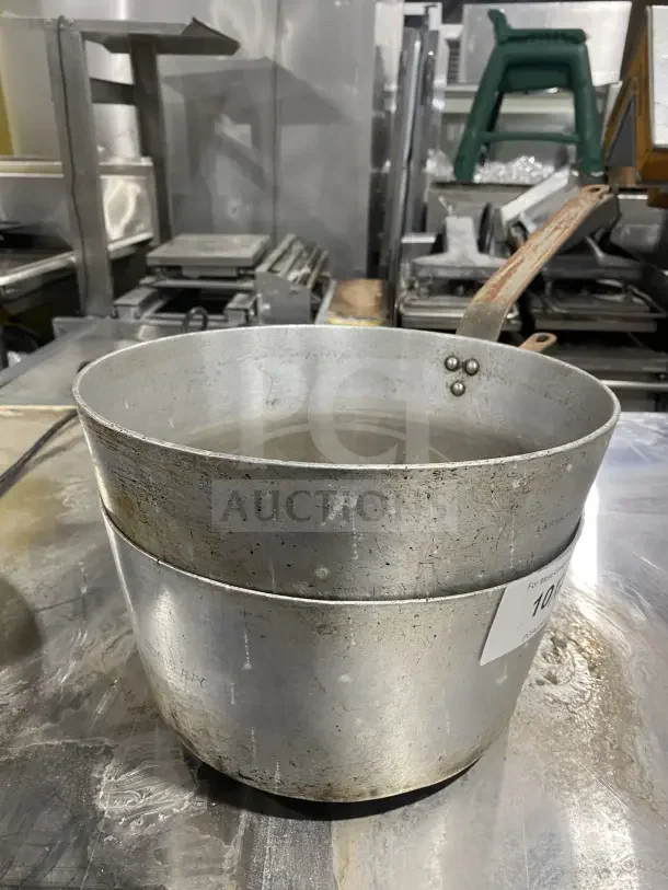 L&G commercial aluminum tapered sauce pans with heavy-duty handles, used condition, visible wear, auction tag attached.