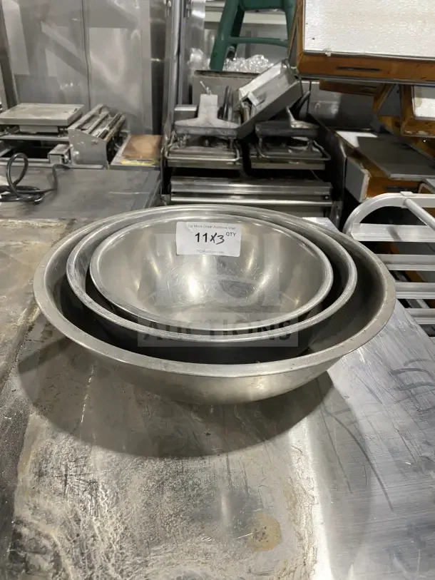 Three commercial stainless steel mixing bowls in varying sizes, in good condition. Auction label indicates lot "11x3" quantity.