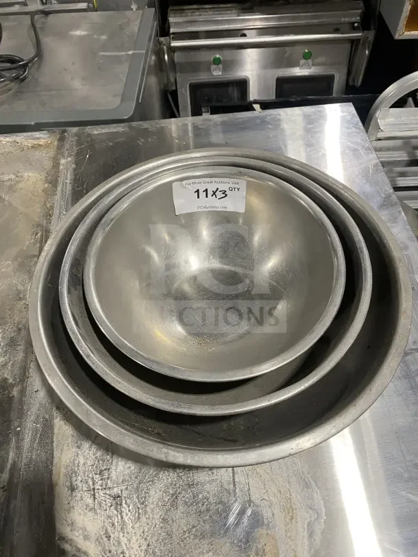 Commercial stainless steel mixing bowls, set of three. Durable design, used condition. Auction lot tag: 11x3 QTY.