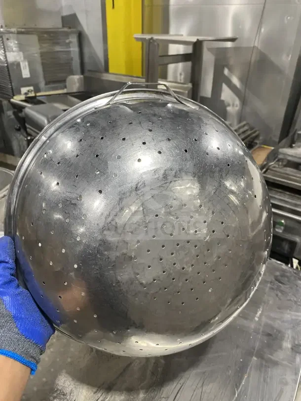 Commercial stainless steel colander, perforated design, durable finish, slightly worn. Includes two colanders per bid.