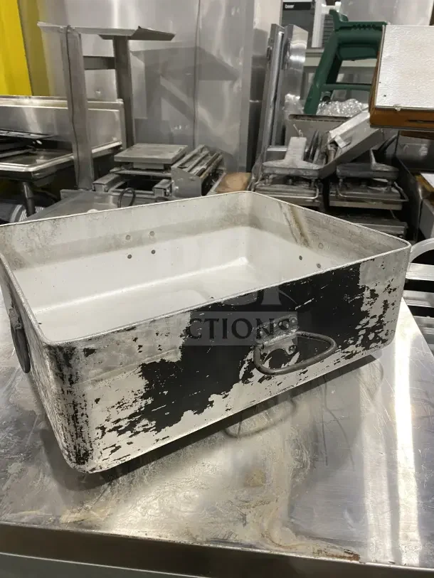 Commercial heavy-duty aluminum roast/bake pan with drop handles, showing signs of wear, ideal for restaurant use.