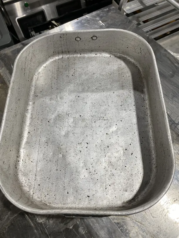 Commercial aluminum roasting pan with handles, visible wear, ideal for large-scale cooking or baking. Set of two.
