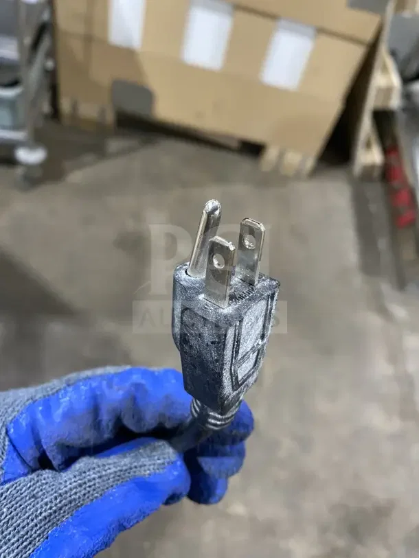 Plug of Dukers DUC48F commercial refrigerator, 115V, 1 phase. Gloved hand holding connector.