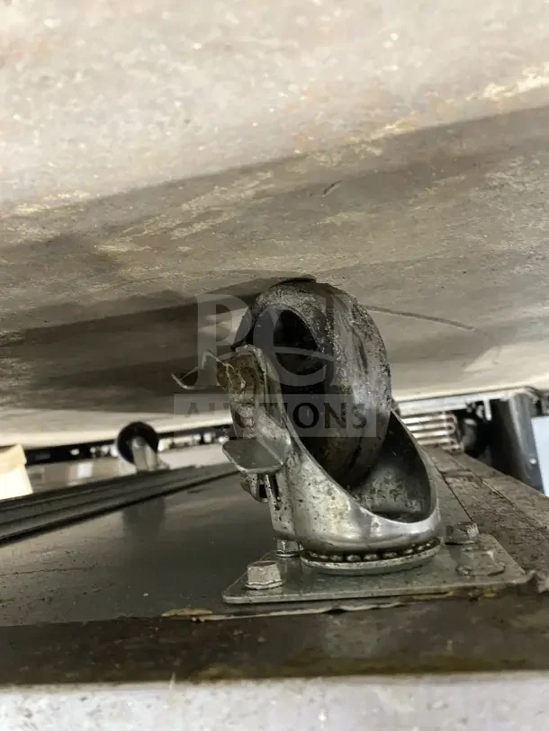 Close-up of a caster on a commercial stainless steel 2-door refrigerated prep station, Model HKN-SPMT48R2E, on casters.