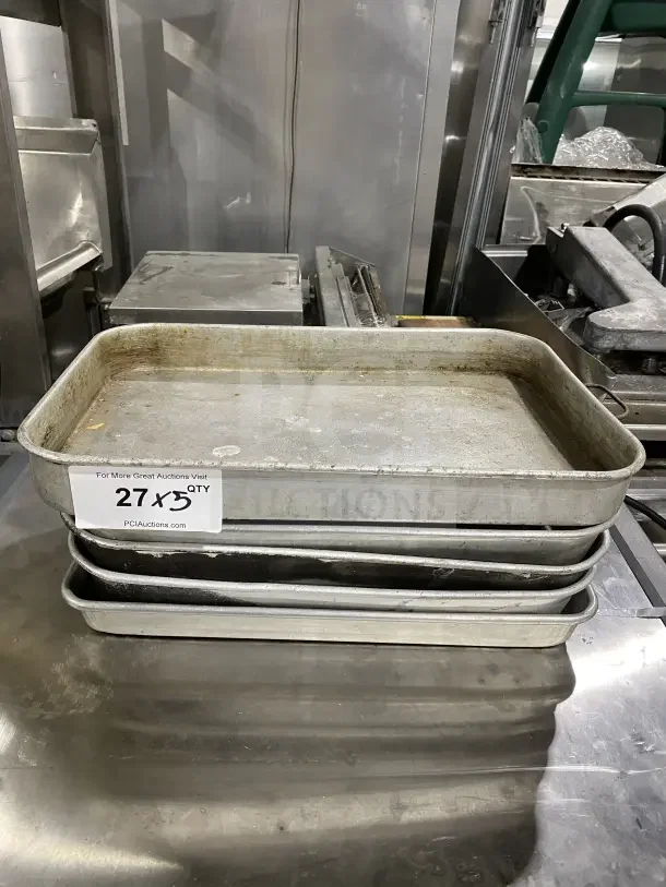 Commercial stainless steel baking trays, stack of five. Used condition with visible wear. Auction label: "27 x 5 QTY".