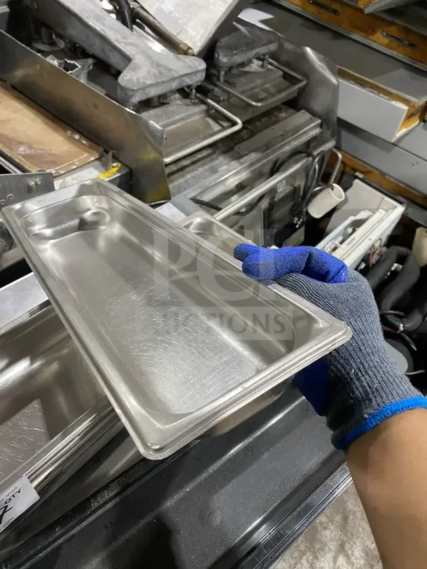 Commercial stainless steel prep tray for cinnamon rolls or salad, heavy-duty, durable, slightly worn surface.
