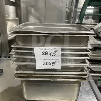 Commercial stainless steel prep trays, stack of five, used condition, ideal for sauce or salad prep in kitchens.