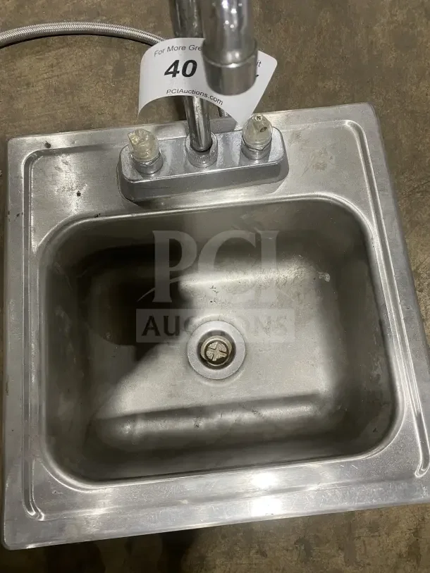 Commercial stainless steel drop-in hand sink with faucet. Visible wear, includes hot and cold knobs, drainage opening. Auction tag number 40 displayed.