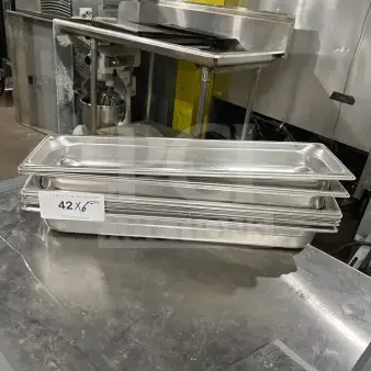 Commercial stainless steel full-size hotel pans stack. Slightly used, set of 6. Tag reads "42 x 6 Qty."