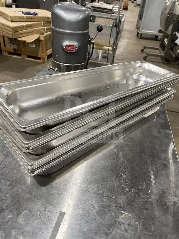 Stack of commercial stainless steel full-size hotel pans, excellent condition, shown on metal table, suitable for catering use.