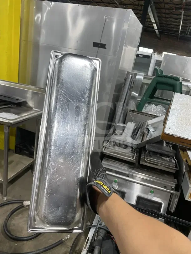 Commercial stainless steel full-size hotel pan, slightly scratched, held vertically. Auction offers six pans per bid.