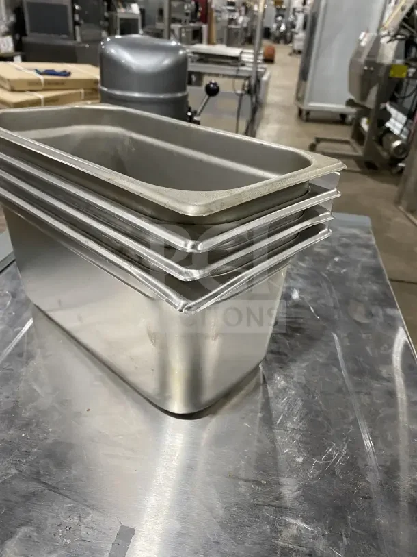 Winco stainless steel half-size hotel pans, Model SPJL306, stacked, lightly used, commercial kitchen setting.