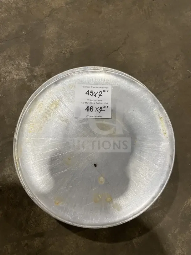 Commercial round aluminum pizza pan with visible wear, marked for auction. Includes label showing quantities available.