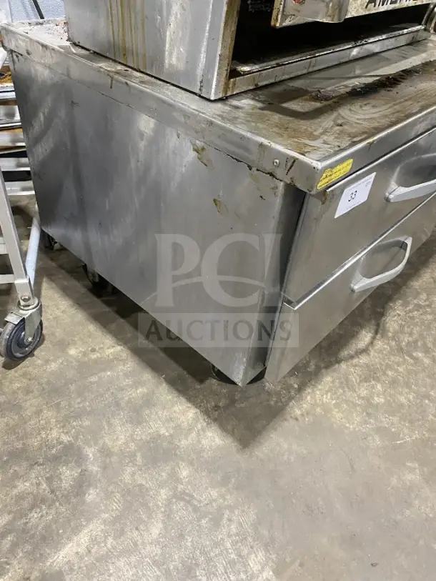 Commercial stainless steel 2-drawer refrigerated chef base on casters, heavy-duty, with visible wear and label markings.