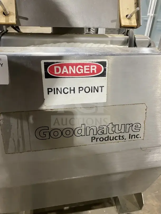 Goodnature commercial stainless steel hydraulic cold press juicer, shown on casters. Features "Danger: Pinch Point" label.