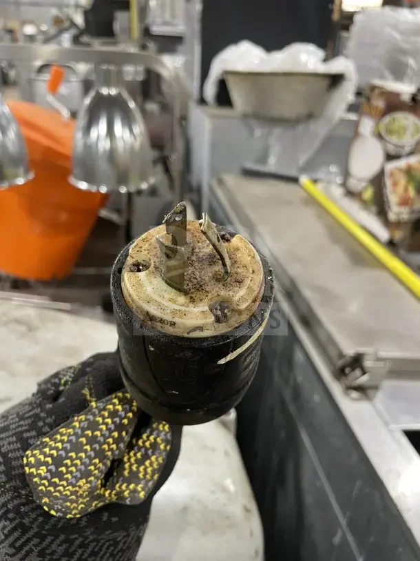 Alt text: Globe SP60P heavy-duty mixer plug, showing wear, held by a gloved hand. Auction item details mentioned.