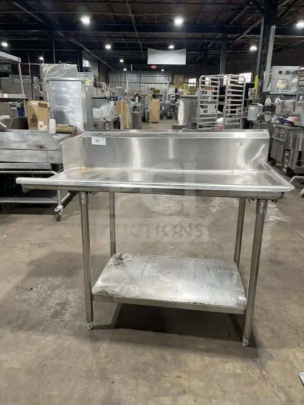 Commercial stainless steel soiled dish table with backsplash, on casters. Includes lower shelf. Appears in good condition.