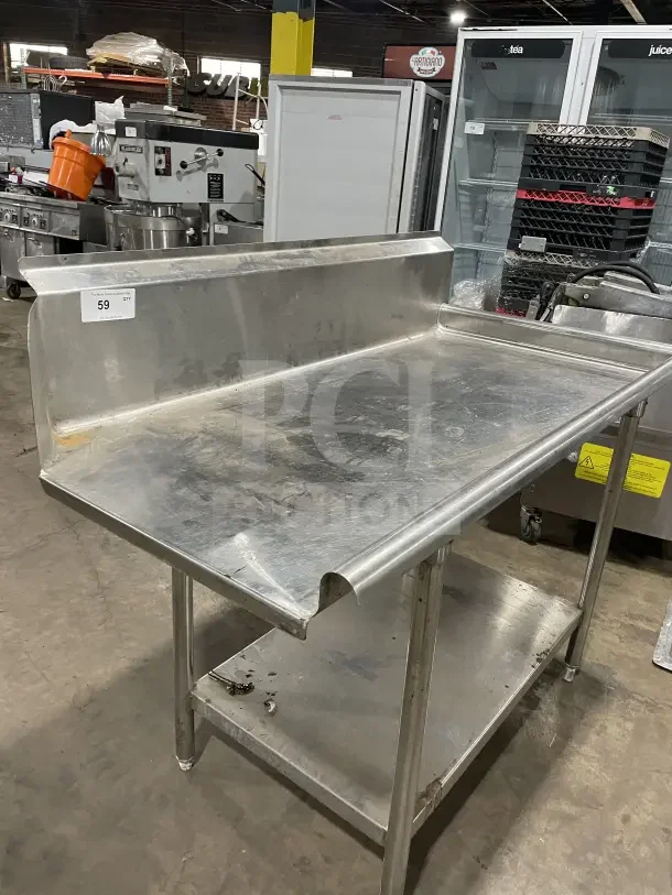 Commercial stainless steel soiled dishtable with backsplash and casters. Shows slight wear, ideal for kitchen use.