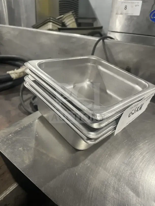 Amko Commercial Stainless Steel Half-Size Steam Table Pan, Model 24602, stack of pans, industrial kitchen setting.