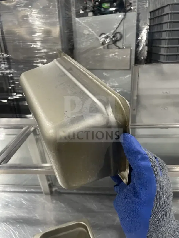 Winco SPJL404 stainless steel half-size steam table pan, commercial grade, moderate wear, held in gloved hand.