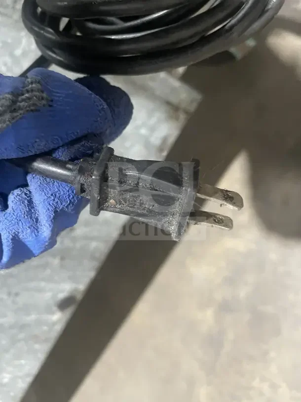 Alt text: Close-up of a plug connected to a commercial stainless steel refrigerated chef base, showing good condition.