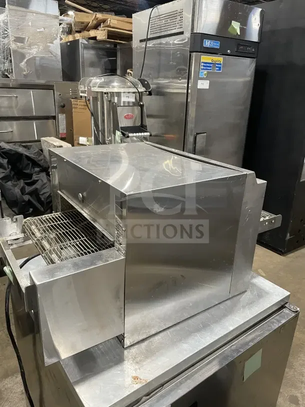 Avantco TTP14240 stainless steel conveyor pizza oven on countertop. Good condition, visible wear. Features adjustable conveyor.