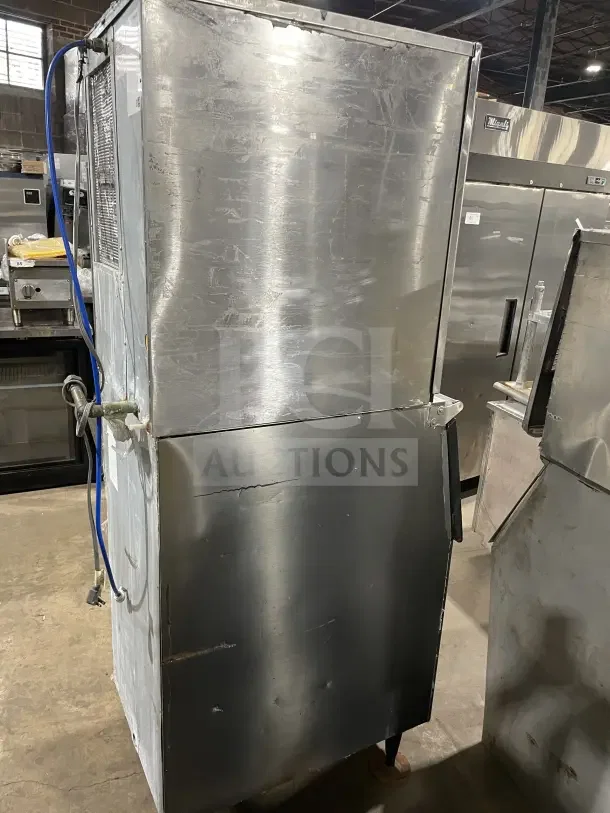 Hoshizaki stainless steel slim-line modular commercial ice machine with storage bin, on legs, shows signs of wear.