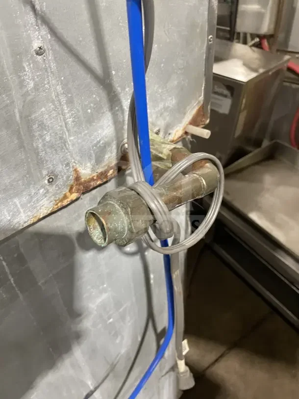 Hoshizaki stainless steel commercial ice machine with storage bin, showing rear connections and some rust. On legs.