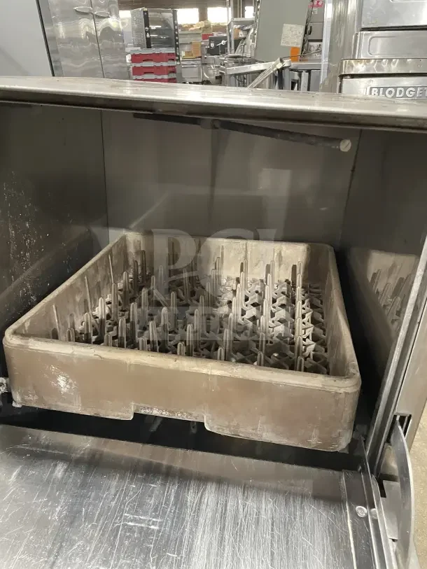 Jackson JP24b stainless steel undercounter dishwasher with poly dish rack, visible wear, commercial kitchen setting.