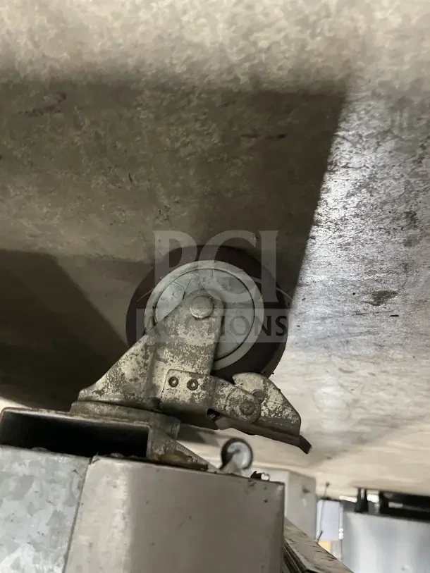 Alt text: Close-up of the caster wheel on a Leader LM72 stainless steel refrigerated prep table, showing wear.