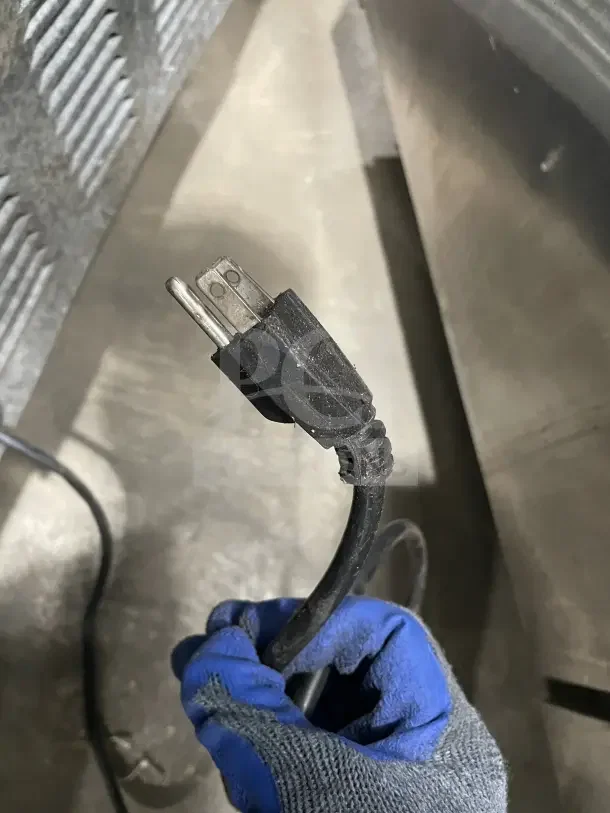Close-up of power plug held by a gloved hand, part of a Leader LM72 refrigerated prep table.