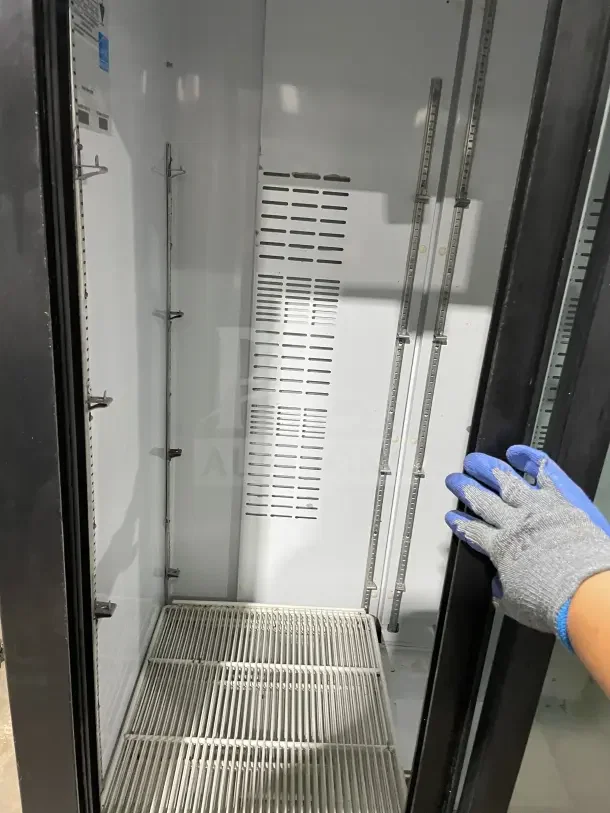 Frigoglass MC1100S-1 refrigerator with double glass sliding doors, poly-coated wire rack, and caster wheels.
