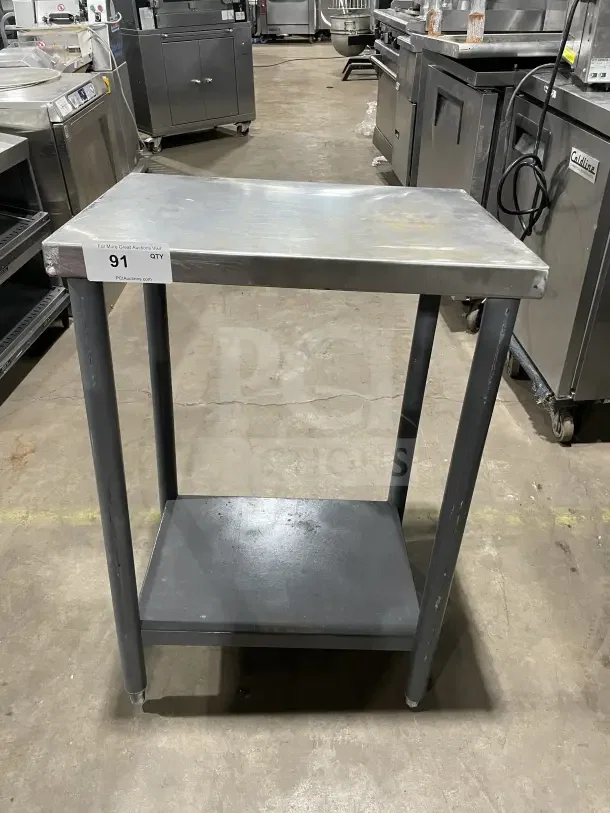 Commercial stainless steel equipment stand on legs, used condition, with two shelves, visible auction tag labeled "91".