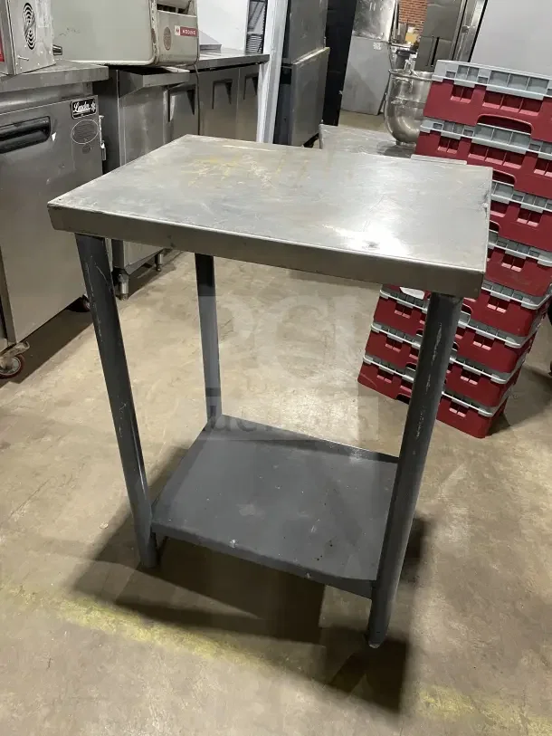 Commercial stainless steel equipment stand with legs, featuring a sturdy top and lower shelf, in used condition.