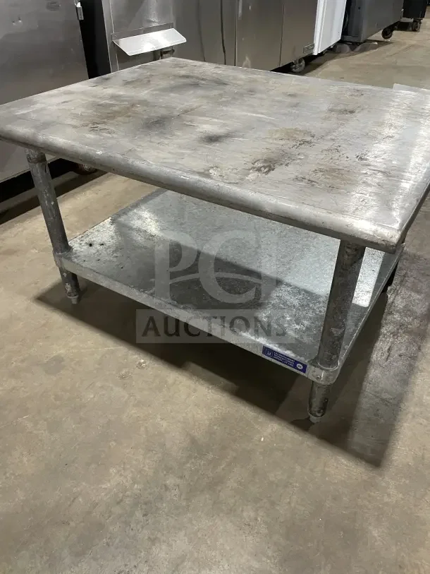 L&J Commercial stainless steel two-compartment equipment stand on legs, showing some wear, tag visible on bottom shelf.
