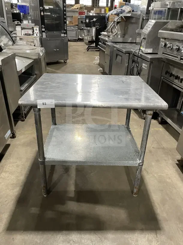 Commercial stainless steel equipment stand with 2 compartments, on legs, used condition, metal surface shows wear.