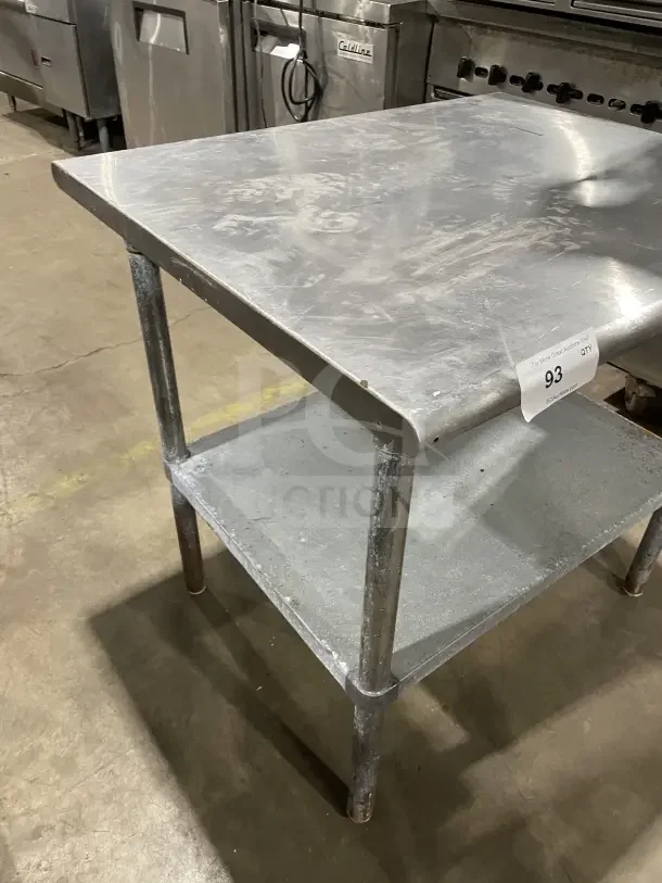 Commercial stainless steel two-compartment equipment stand, on sturdy legs, showing surface wear, suitable for industrial use.