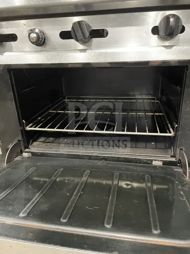 Wolf commercial stainless steel gas range, 4 burners, with back and sides, on casters. Features control knobs and oven rack.