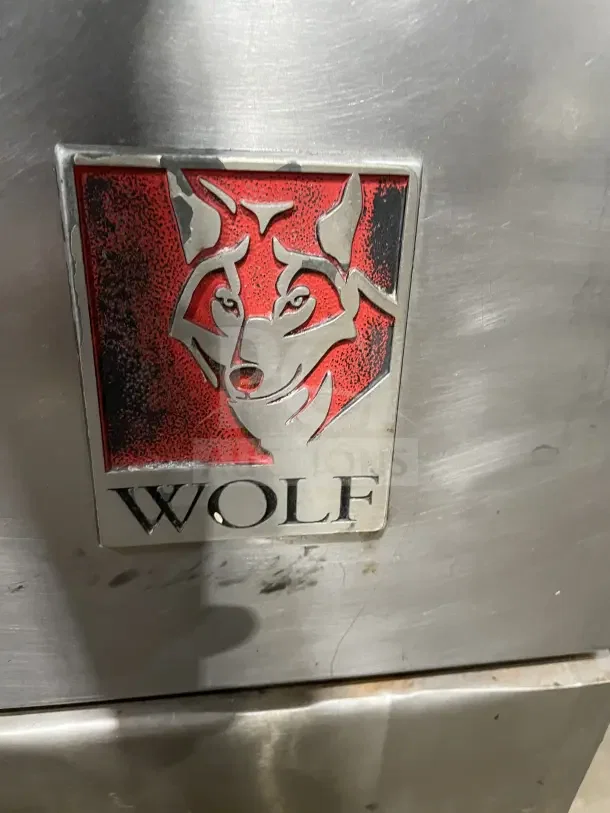 Wolf commercial stainless steel gas range with 4 burners, back and sides. Features on casters. Wolf logo visible.