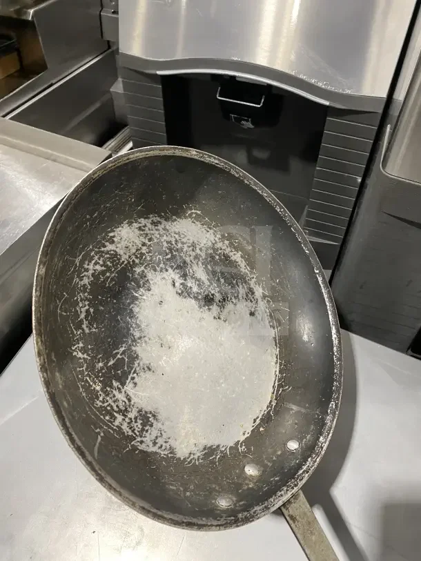 Commercial aluminum non-stick fry pan with wear, featuring a removable red silicone sleeve. Ideal for professional kitchens.