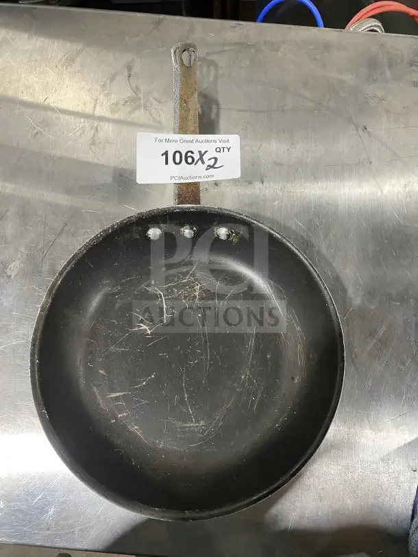 Commercial aluminum non-stick fry pan with handle, lightly scratched, auction label "106X2" visible, bid for two pans.
