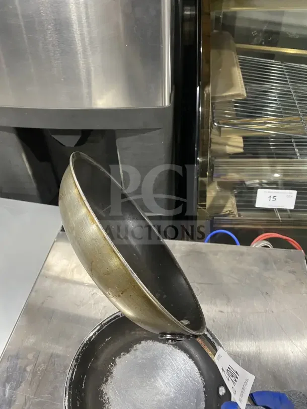 Commercial aluminum non-stick fry pans with handles, shown in fair used condition, auction tag visible.