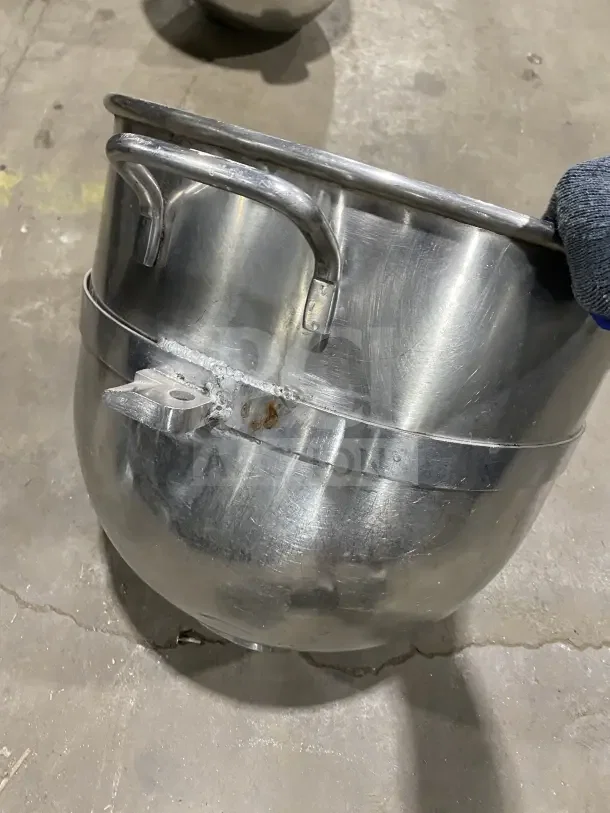 Commercial stainless steel mixing bowl with handles, robust and durable, some wear visible, ideal for heavy-duty use.